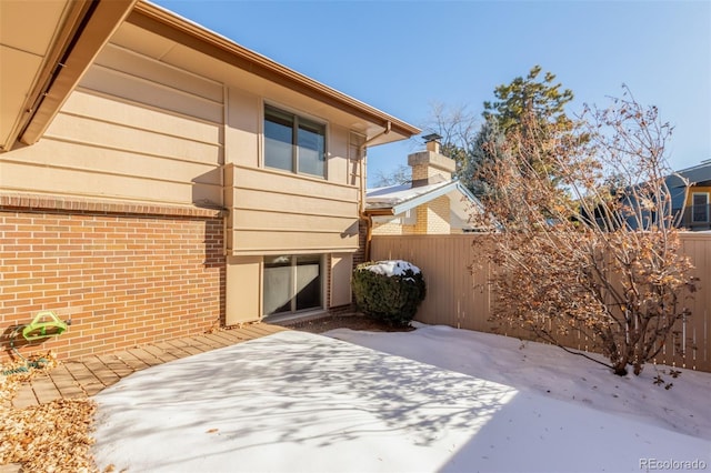 view of home's exterior with brick siding, a patio area, and fence