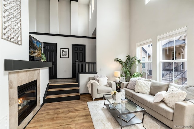 living area with a fireplace, wood finished floors, and a towering ceiling