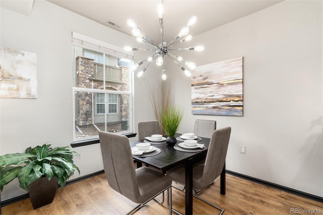 dining space featuring visible vents, wood finished floors, and an inviting chandelier