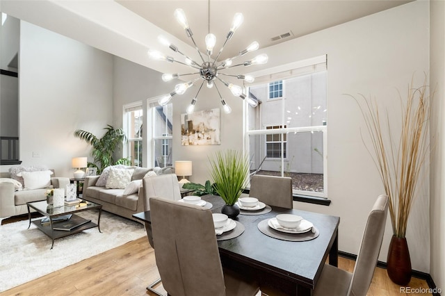 dining room with visible vents, wood finished floors, and a notable chandelier