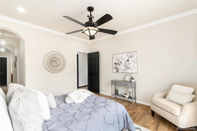 bedroom featuring crown molding, arched walkways, baseboards, and wood finished floors