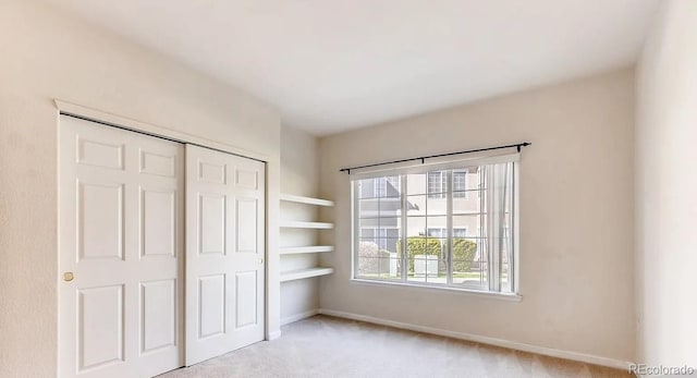 unfurnished bedroom featuring light colored carpet and a closet