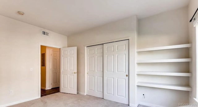 unfurnished bedroom with light carpet and a closet