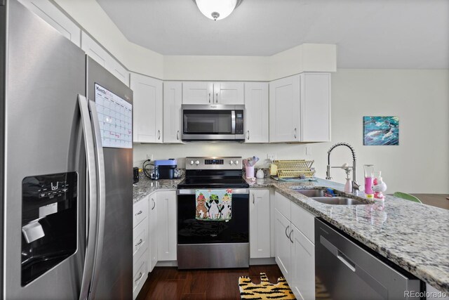 kitchen featuring appliances with stainless steel finishes, a sink, light stone counters, and white cabinetry