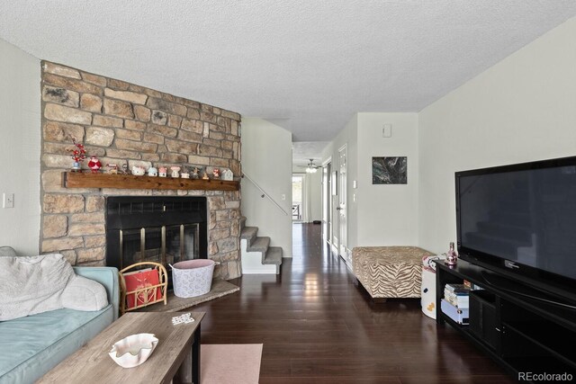 living area featuring wood finished floors, a ceiling fan, a textured ceiling, stairway, and a fireplace