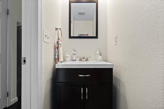 bathroom with vanity and a textured wall