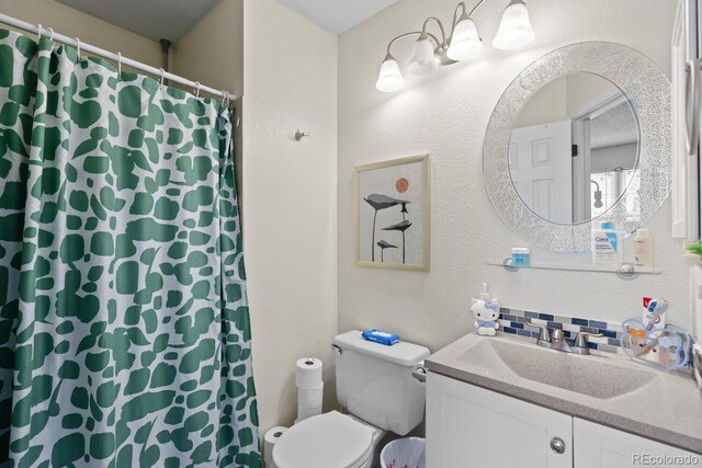 full bathroom featuring toilet, vanity, a textured wall, and a shower with curtain