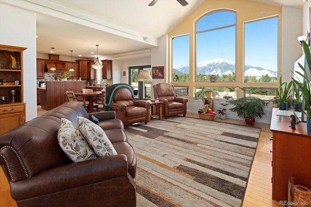 living room with lofted ceiling, ceiling fan, a mountain view, and light hardwood / wood-style flooring