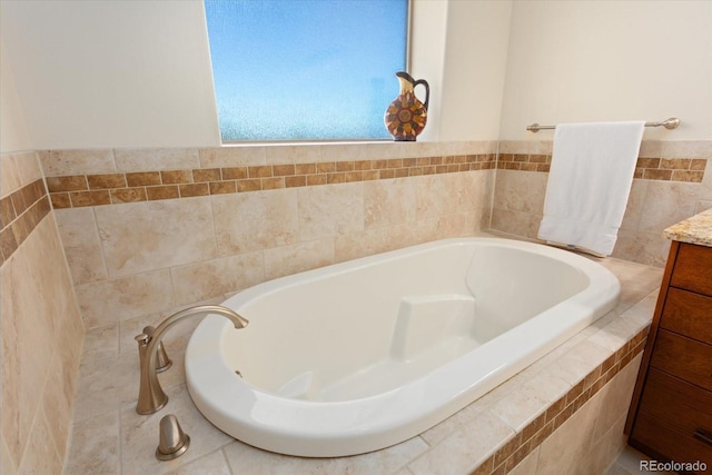 bathroom with tiled tub and vanity