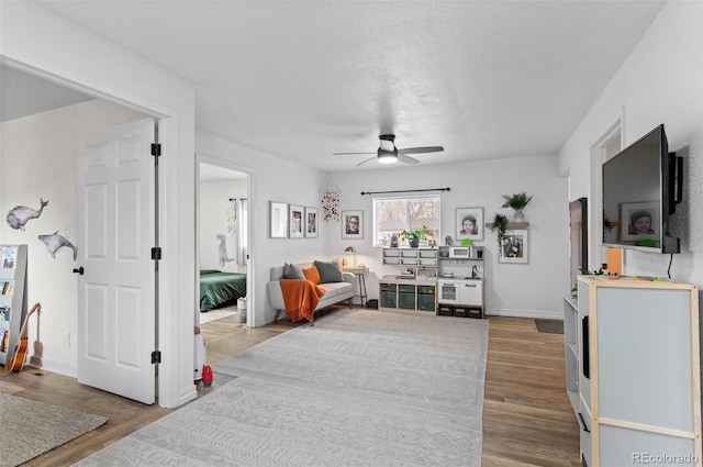 living room featuring a textured ceiling, wood-type flooring, and ceiling fan