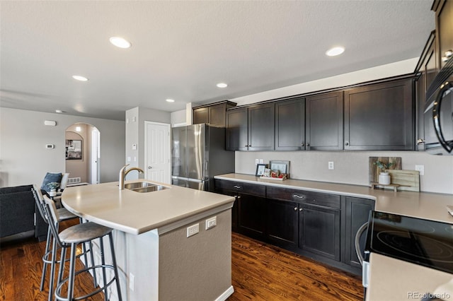 kitchen featuring a kitchen island with sink, sink, dark wood-type flooring, and stainless steel appliances