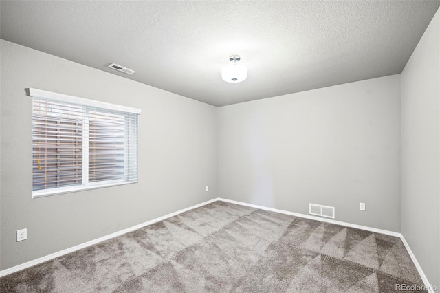 empty room with carpet floors and a textured ceiling