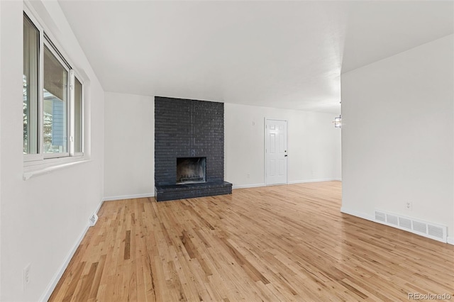 unfurnished living room with light hardwood / wood-style floors and a brick fireplace