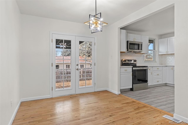 kitchen featuring pendant lighting, white cabinets, light hardwood / wood-style flooring, appliances with stainless steel finishes, and tasteful backsplash