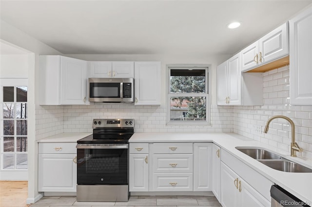 kitchen featuring white cabinets, decorative backsplash, sink, and appliances with stainless steel finishes