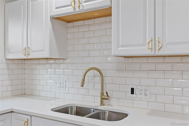 kitchen with decorative backsplash, white cabinets, and sink