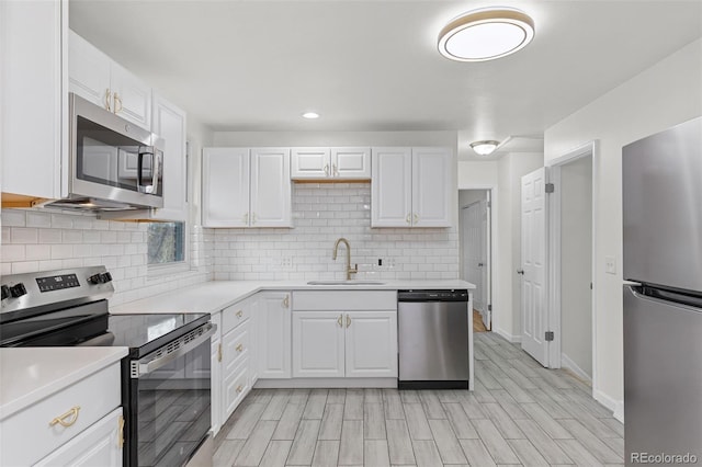 kitchen featuring sink, light hardwood / wood-style flooring, appliances with stainless steel finishes, tasteful backsplash, and white cabinetry