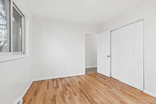 unfurnished bedroom with light wood-type flooring and a closet