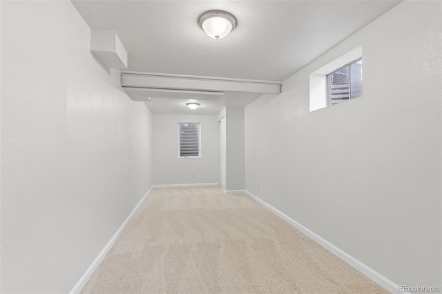 basement featuring a textured ceiling and light carpet