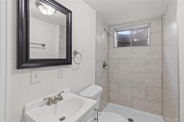 bathroom featuring vanity, toilet, and a tile shower