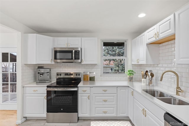 kitchen featuring tasteful backsplash, sink, white cabinets, and appliances with stainless steel finishes