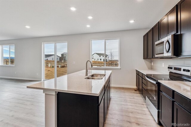 14441 Clover Dr, Mead, CO 80504 - kitchen featuring a sink, stainless steel appliances, light wood finished floors, a kitchen island with sink, and baseboards