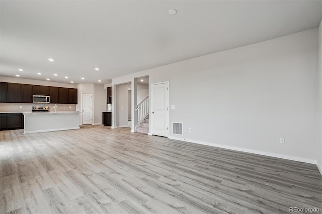 14441 Clover Dr, Mead, CO 80504 - unfurnished living room featuring light wood-style floors, recessed lighting, baseboards, and stairway