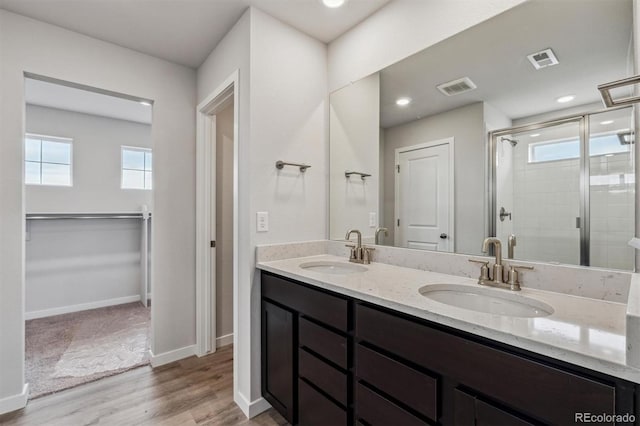 14441 Clover Dr, Mead, CO 80504 - full bathroom featuring double vanity, a stall shower, wood finished floors, baseboards, and a spacious closet