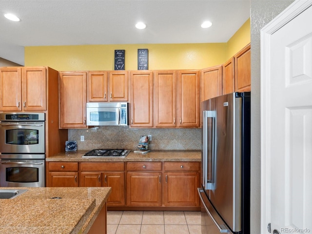 3853 S Malta St, Aurora, CO 80013 - kitchen featuring appliances with stainless steel finishes, decorative backsplash, light tile patterned floors, light stone counters, and recessed lighting