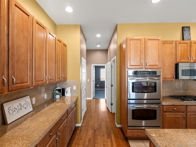 3853 S Malta St, Aurora, CO 80013 - kitchen with stainless steel appliances, wood finished floors, backsplash, recessed lighting, and light stone countertops