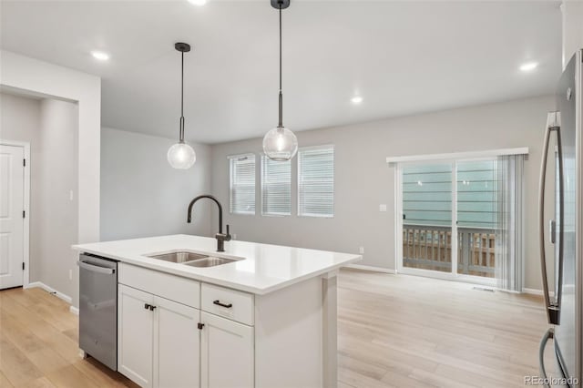 kitchen with stainless steel appliances, a kitchen island with sink, sink, white cabinets, and hanging light fixtures