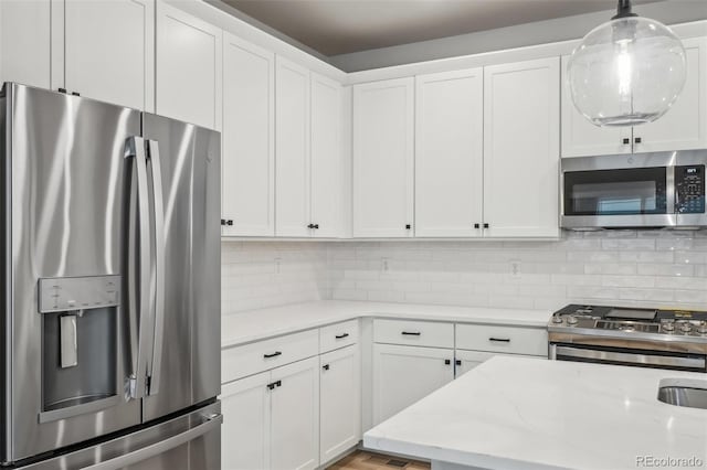 kitchen featuring backsplash, white cabinetry, stainless steel appliances, and decorative light fixtures