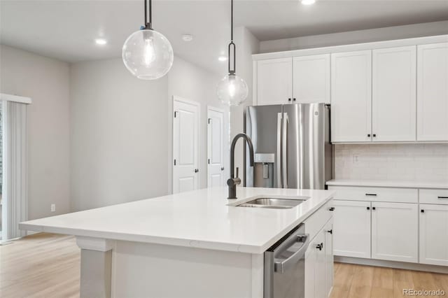 kitchen with tasteful backsplash, stainless steel appliances, pendant lighting, a center island with sink, and white cabinetry