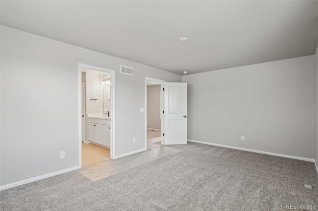 unfurnished bedroom with ensuite bathroom and light colored carpet