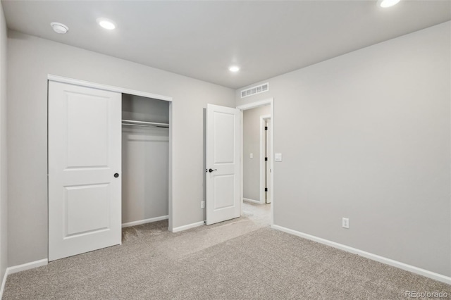 unfurnished bedroom featuring light colored carpet and a closet