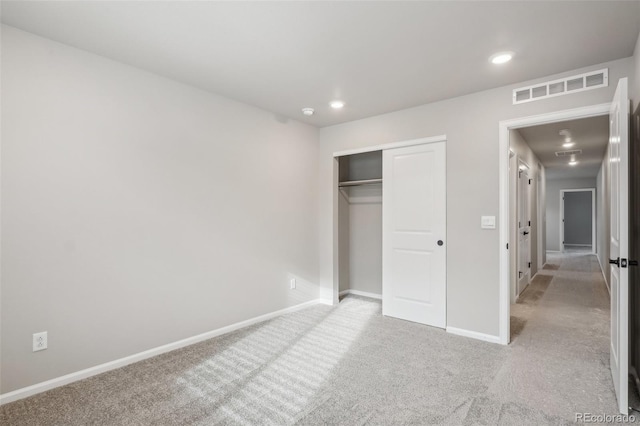 unfurnished bedroom featuring light carpet and a closet