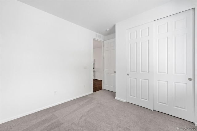 unfurnished bedroom with a closet and light colored carpet