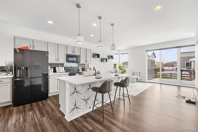 kitchen with an island with sink, dark hardwood / wood-style floors, sink, and black appliances