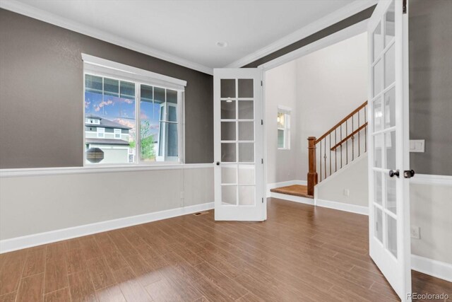 spare room with french doors, wood finished floors, crown molding, stairs, and baseboards