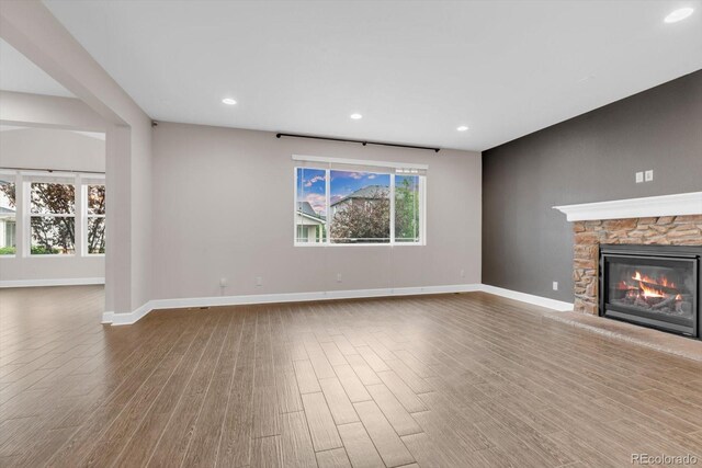 unfurnished living room with baseboards, wood finished floors, a fireplace, and recessed lighting