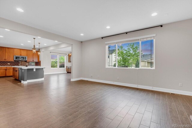 unfurnished living room with wood finished floors, baseboards, and recessed lighting