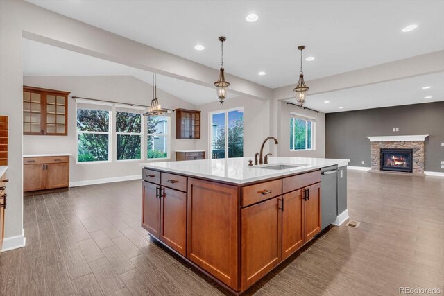 kitchen featuring a sink, stainless steel dishwasher, dark wood-style flooring, brown cabinetry, and a fireplace