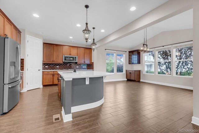 kitchen with stainless steel appliances, a sink, tasteful backsplash, light countertops, and lofted ceiling