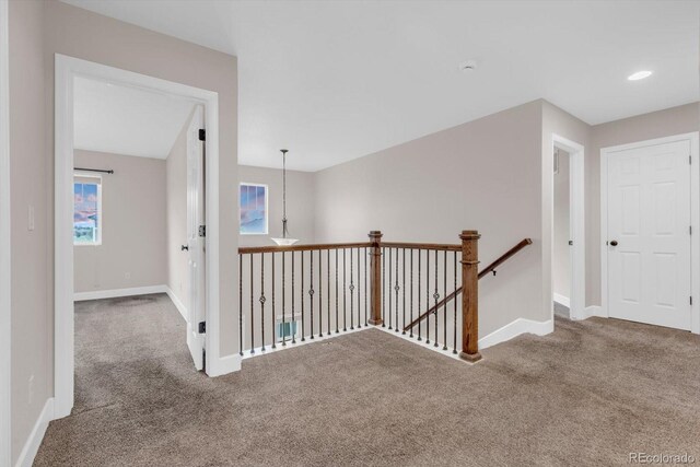hall featuring carpet flooring, an upstairs landing, and baseboards