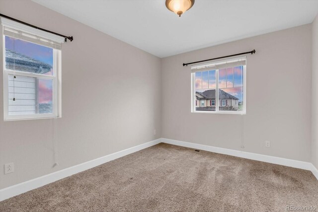 carpeted empty room featuring baseboards