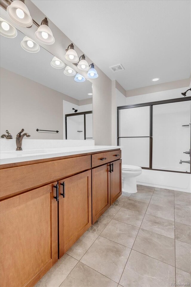 bathroom with toilet, tile patterned floors, enclosed tub / shower combo, and vanity