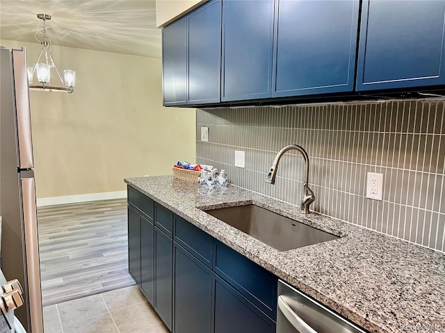 kitchen featuring stainless steel appliances, sink, blue cabinetry, and decorative backsplash