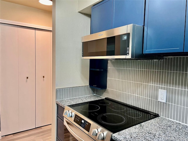 kitchen featuring light hardwood / wood-style flooring, backsplash, electric range, blue cabinetry, and light stone counters