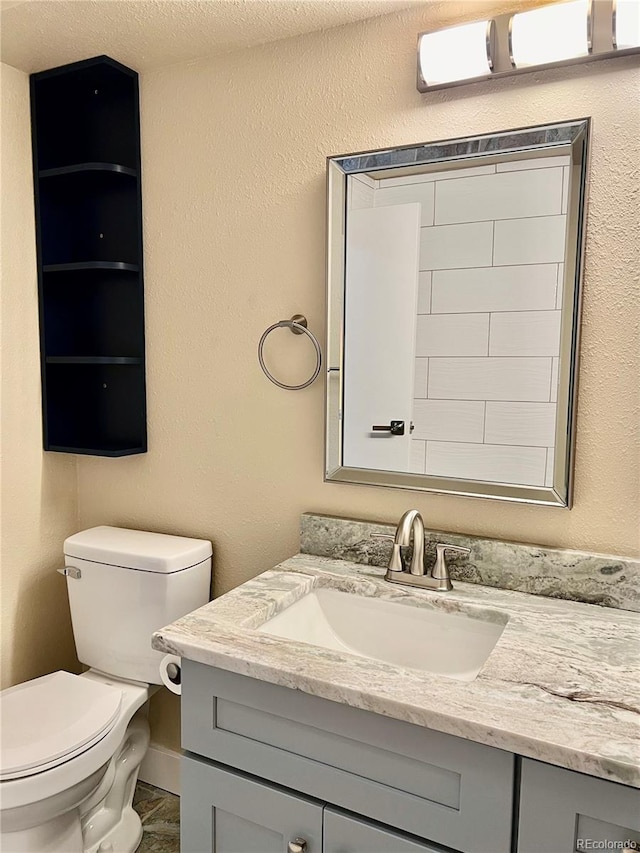 bathroom with vanity, a textured ceiling, and toilet