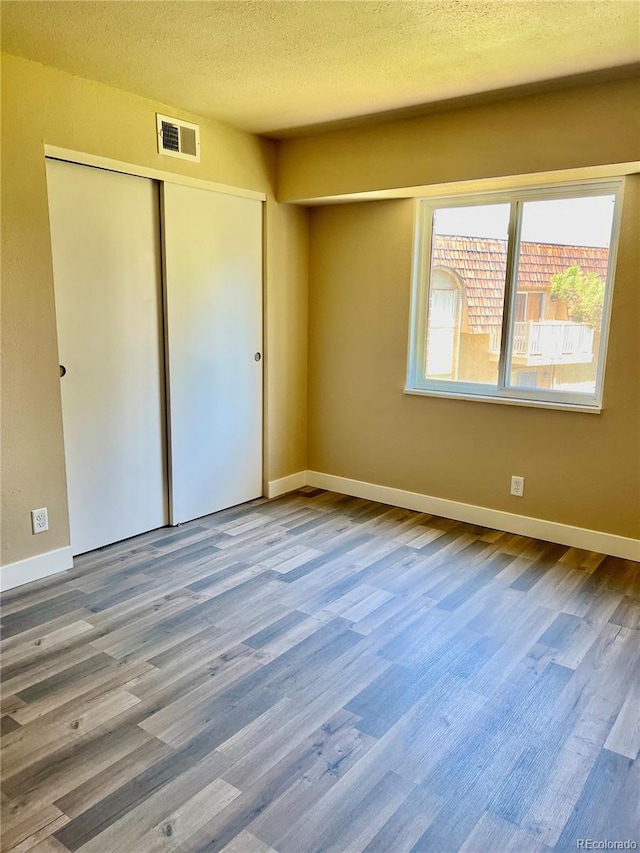 unfurnished bedroom with hardwood / wood-style floors, a textured ceiling, and a closet